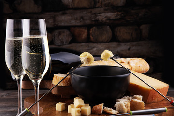 Gourmet Swiss fondue dinner on a winter evening with assorted cheeses on a board alongside a heated...