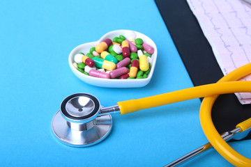 Stethoscope, RX prescription and colorful assortment pills and capsules on plate.