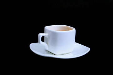 White cup of classic espresso coffee and pralines on black background.