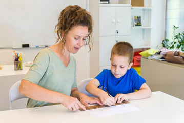 teacher woman learn to use ruler to preschooler boy in the classroom