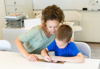 teacher woman learn to use ruler to preschooler boy in the classroom