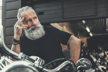 Mindful elder man locating on motorbike