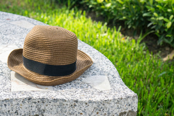 Fototapeta na wymiar Brown straw hat on marble chair or bench in the park. with copy space for text.