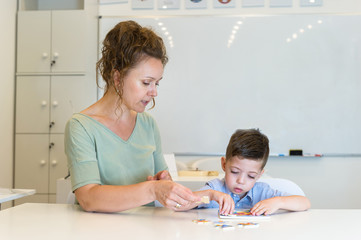 teacher woman and preschooler boy playing with puzzle game in the classroom