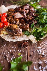 Shish-kebab with grilled vegetables on lavash. Meat, field mushrooms and cherry tomatoes with herbs, barbecue and natural food preparing in restaurant, close up