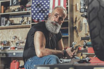 Fototapeta na wymiar Thoughtful mature man holding tool in reapair shop