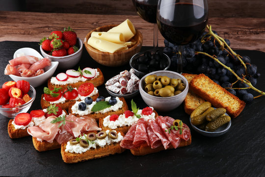 Italian antipasti wine snacks set. Cheese variety, Mediterranean olives, pickles, Prosciutto di Parma, tomatoes and wine in glasses. Spanish tapas