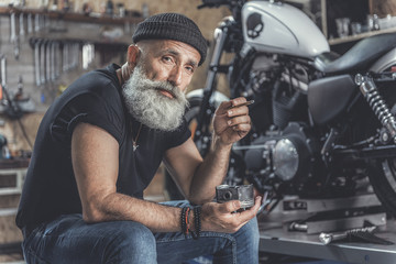 Obraz na płótnie Canvas Thoughtful elder man locating nearby motorbike