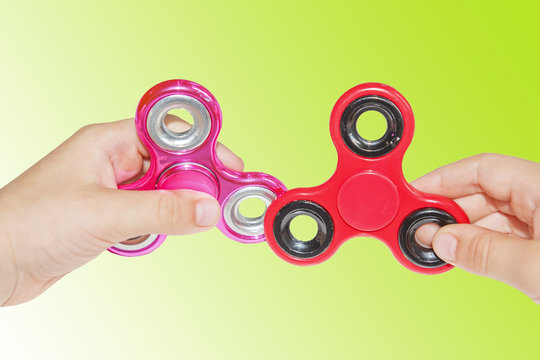 two fidget spinners in hand of boy on green background