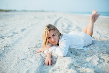 Fototapeta na wymiar Happy young woman laying on beach and looking on copy space