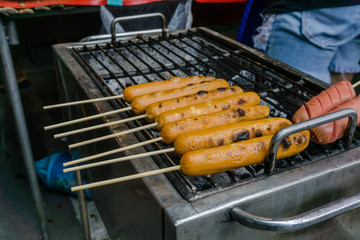 Thai Meat Balls and Hot Dogs in grilling process at the market.