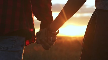 Young couple in love walking in the field holding hands - Powered by Adobe