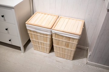 Wooden squared laundry baskets with linen standing against white wall