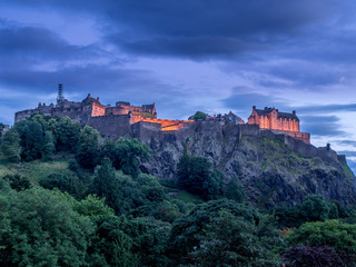View of Edinburgh Castle looming over the beautiful city of Edinburgh at night.