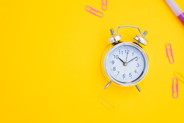 back to school or office styed scene with alarm clock and copy space on yellow background