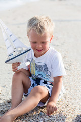 Baby boy playing with ship toy at sea. Child os on vacation in summer at the beach on vacations
