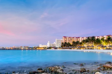 Foto op Canvas High Rise hotelgebied in Aruba in de schemering. Palmbomen in beweging suggereren het winderige weer, een bekend kenmerk van dit eiland, gelegen aan de zuidelijke rand van het Caribisch gebied © mandritoiu