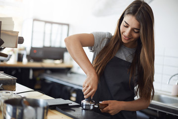 Young and beautiful female barista tamping espresso shot - obrazy, fototapety, plakaty