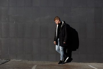 Obraz premium Young stylish redhead man in trendy outfit posing against urban background