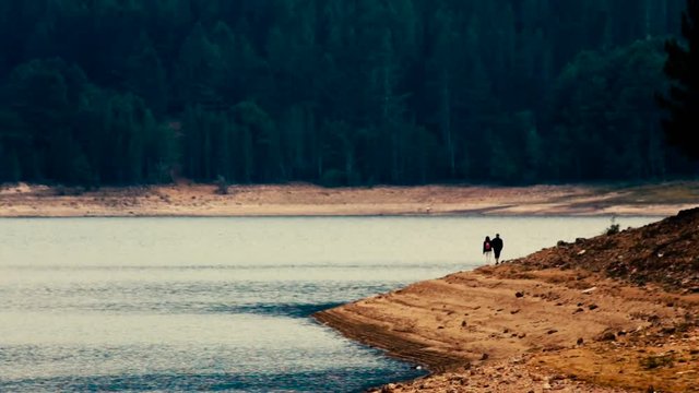 romantic couple walking on the lake shore