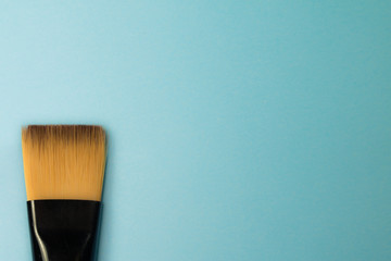 artistic concept flat paint brush with natural sable hair bristles on blue turquoise background...