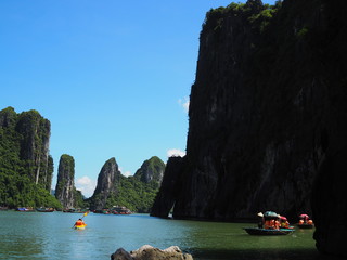 Tourist bamboo boat with silhouette high cliff edge in Ha long bay, Vietnam