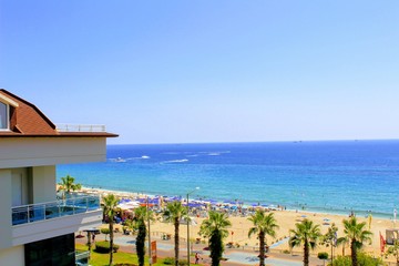 View of the embankment of the city of Alanya and Cleopatra Beach: the sea, sand, palm trees, sun beds and beach umbrellas.
