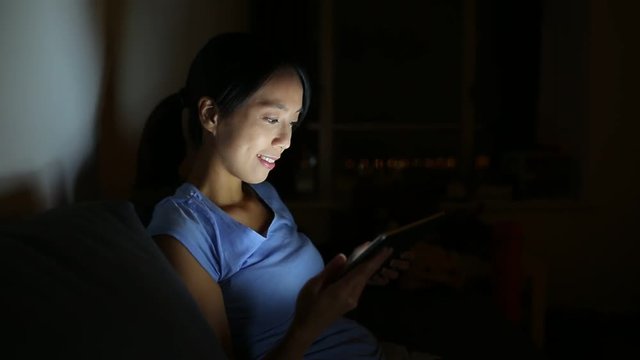 Woman using digital tablet at night
