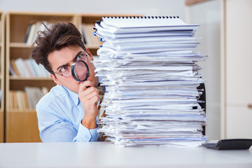 Funny auditor checking reports with magnifying glass