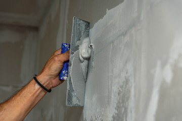 old manual worker with wall plastering tools renovating house