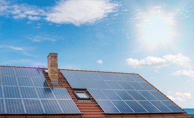 Photovoltaic or solar panels on roof against blue sky.