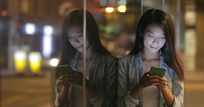 Woman using on mobile phone and waiting for friends in the street