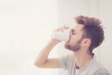 american man with cup of coffee in bedroom with morning.