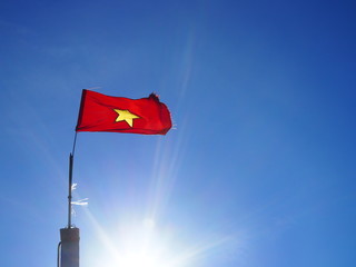 Vietnam national flag in blue sky with sun shining