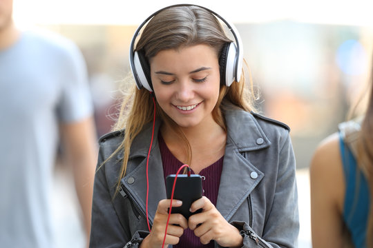 Girl listening to music and walking on the street