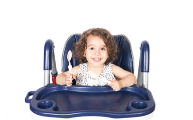 The girl sitting in the baby chair is expecting a meal
