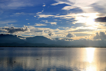 Beautiful sunset and evening sky with mountain and clouds and sunset reflected in the lake for background. Countryside Landscape Under Scenic Colorful Sky At Sunset Dawn Sunrise.
