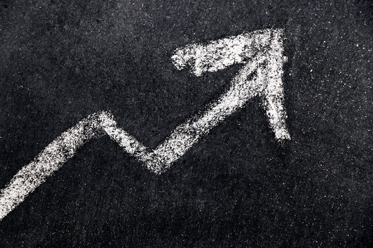 White chalk draw as upward arrow graph on black board background (Concept for sale, profit, cost of company in uptrend)