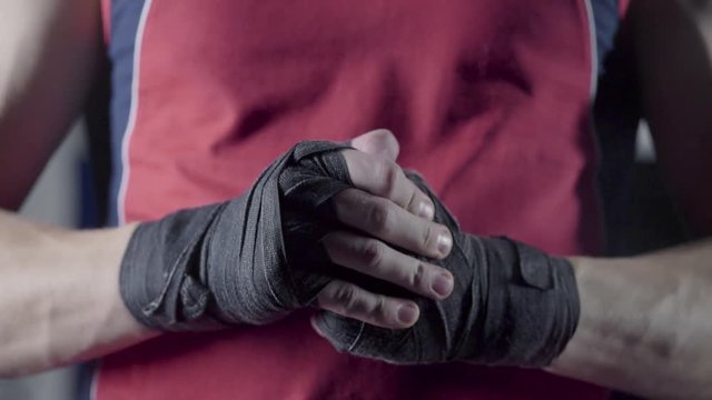 Man flexing his fists before a fight. Close-up of a young Thai boxer hands hemp ropes are wrapped before the fight or training.