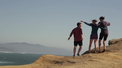 Group Of Close Friends Celebrate And Hug On A Seaside Cliff Overlooking The Oregon Coast