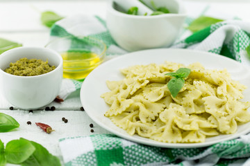  Farfalle pasta with pesto genovese (basil sauce) on white rustic wooden table. Italian cuisine