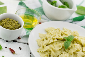  Farfalle pasta with pesto genovese (basil sauce) on white rustic wooden table. Italian cuisine