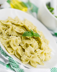 Farfalle pasta with pesto genovese (basil sauce) on white rustic wooden table. Italian cuisine