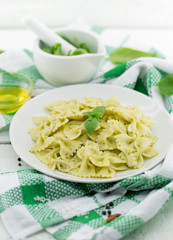  Farfalle pasta with pesto genovese (basil sauce) on white rustic wooden table. Italian cuisine
