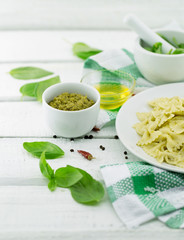  Farfalle pasta with pesto genovese (basil sauce) on white rustic wooden table. Italian cuisine