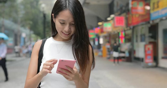 Young Asian Woman texting on cellphone outdoor in a city