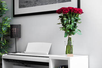 Bouquet of  red Roses on the white table with white piano in background