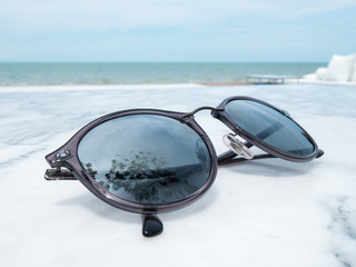 sunglasses on marble table,reflect the tree in front of the beach