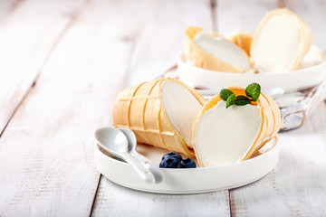 Ice cream in a wafer cup in a plate on a light wooden background. Selective focus. Copy space
