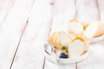 Ice cream in a wafer cup in a plate on a light wooden background. Selective focus. Copy space